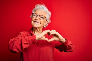 A lady showing a sign of heart with red background as part of Heart health month